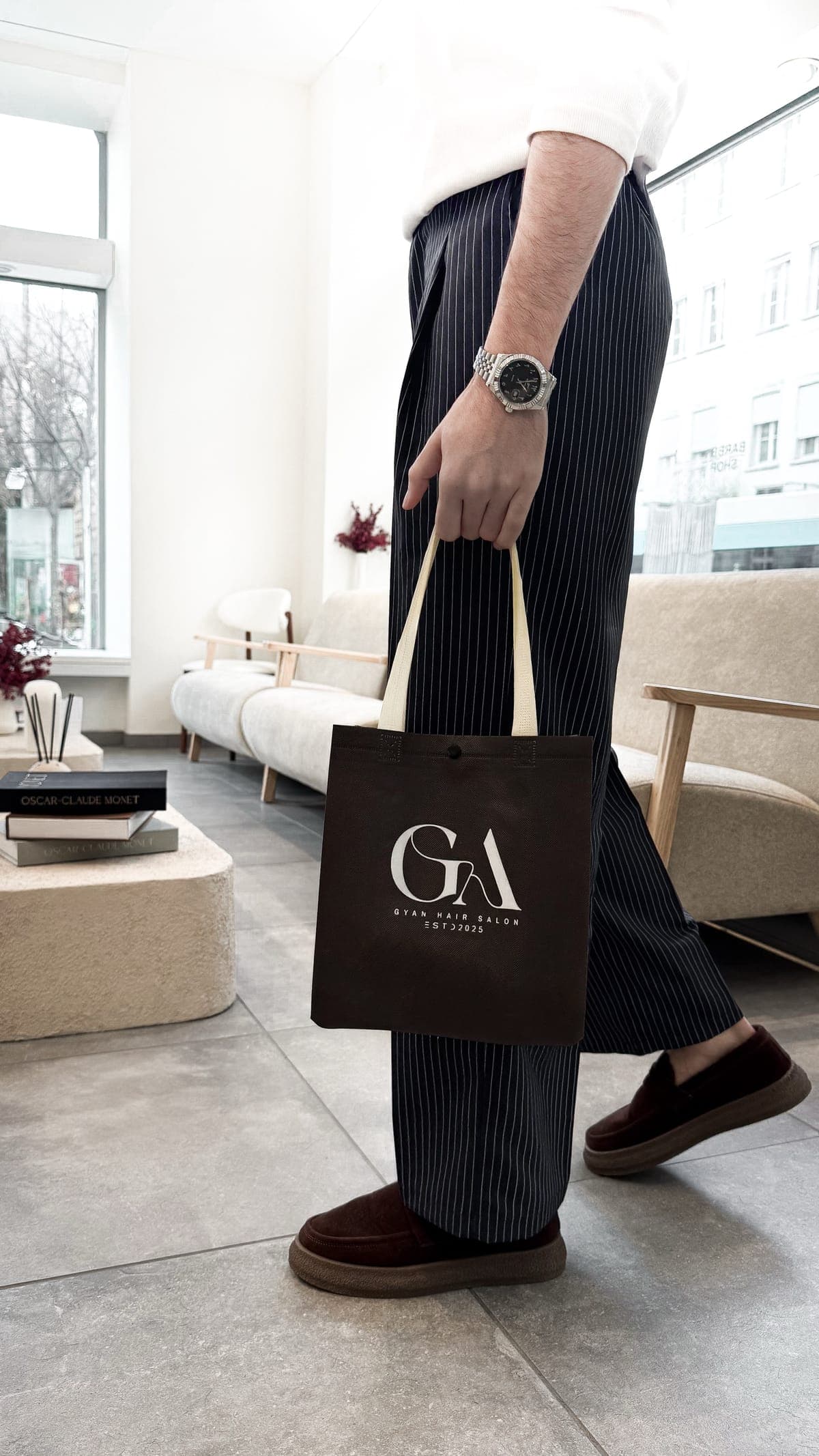 Client avec un sac GYAN brun dans le lounge lumineux du salon